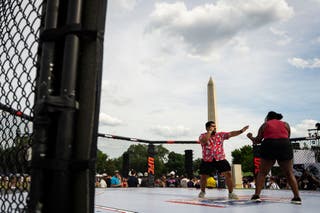 Attendees pose for a photo in a recreation of the UFC Octagon ring at the Ultimate Fighting Championship Fan Fest on the Ellipse